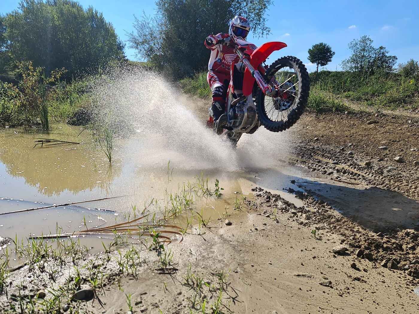 Enduro Training: Enduro-Fahrer durchquert einen Bach, das Wasser spritzt hoch