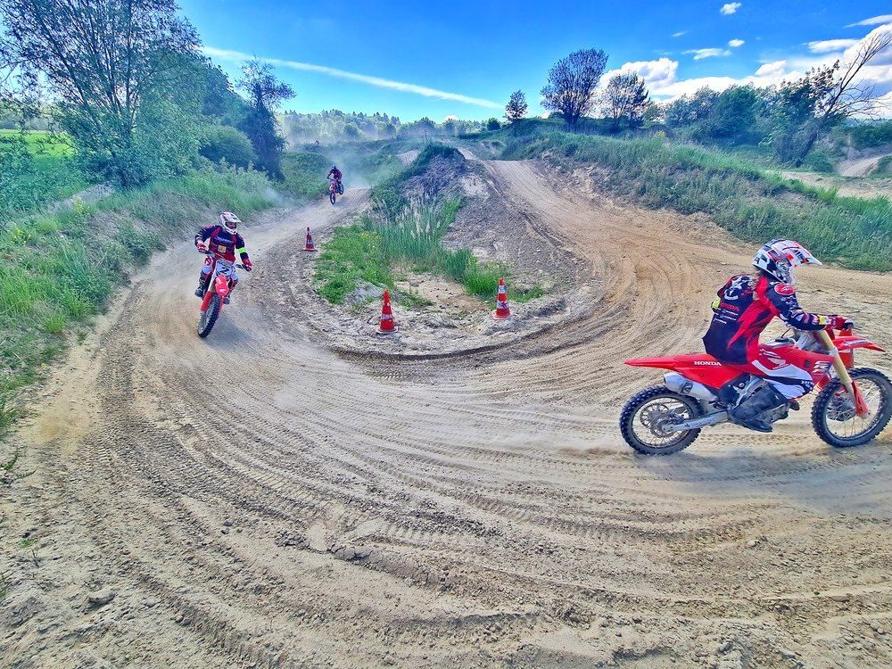 Motocross Kurs: Einsteiger auf roter Honda fährt auf der Übungsstrecke zwischen Pylonen hindurch