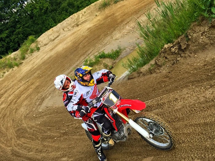 Motocross lernen als Erwachsener: Trainer fährt in der Kurve hinter einer Anfängerin und zeigt ihr die Linie
